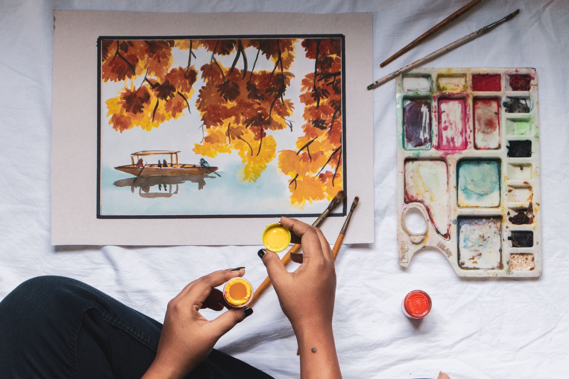 faceless painter with bright paint near artwork on creased sheet